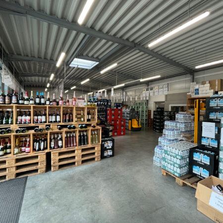 Innenansicht von Sattel's Getränke in Altenessen mit Regalen voller Weinflaschen und Getränkekisten, die Vielfalt des Angebots zeigend.
