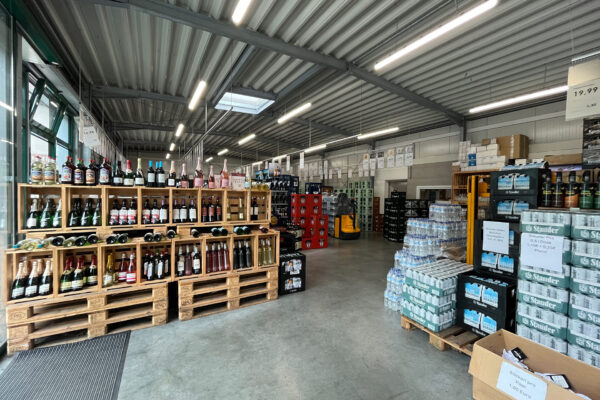 Innenansicht von Sattel's Getränke in Altenessen mit Regalen voller Weinflaschen und Getränkekisten, die Vielfalt des Angebots zeigend.